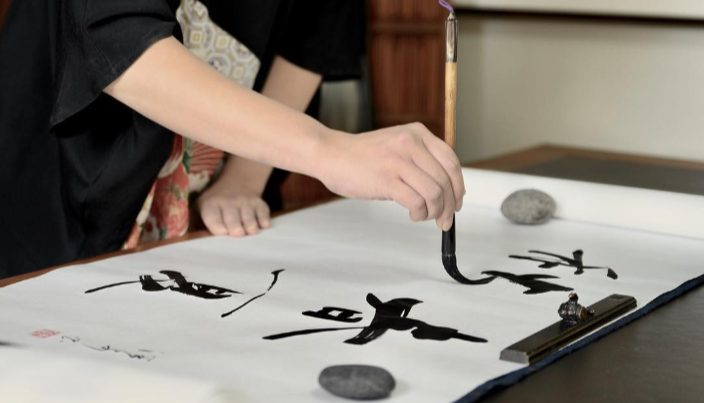 A calligraphy artist writing with traditional Japanese ink and brush