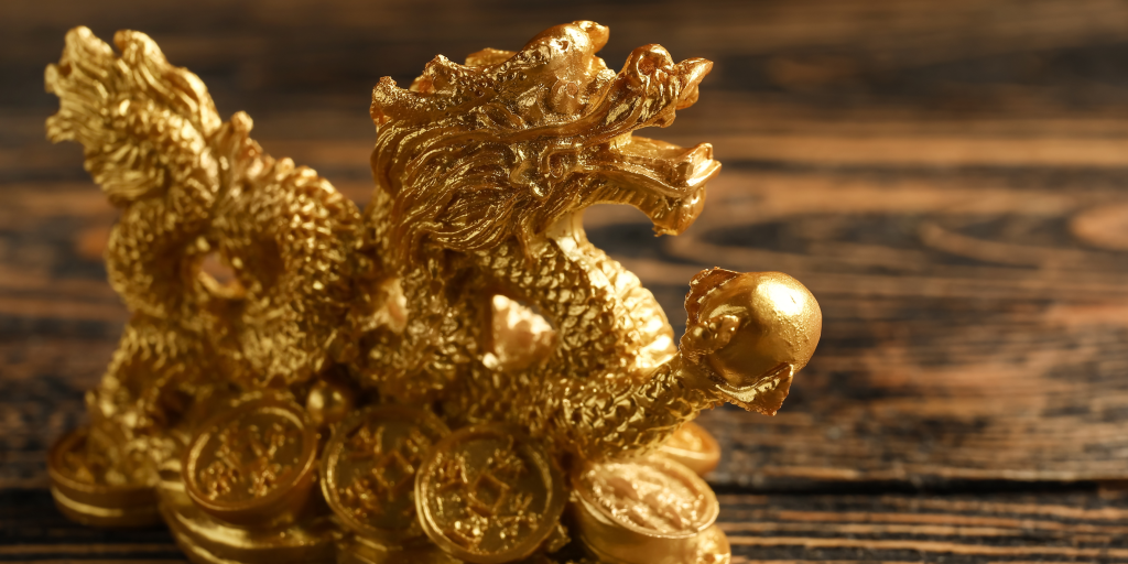 Celebrating Lunar New Year in the Classroom - the picture is of a gold eastern dragon statue holding a pearl in one claw and sitting on a pile of gold coins.