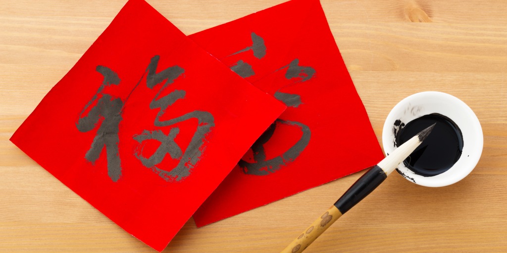 Celebrating Lunar New Year in the Classroom - the picture is of the Chinese character for 'fortune' in calligraphy on red paper with and ink brush next to it.