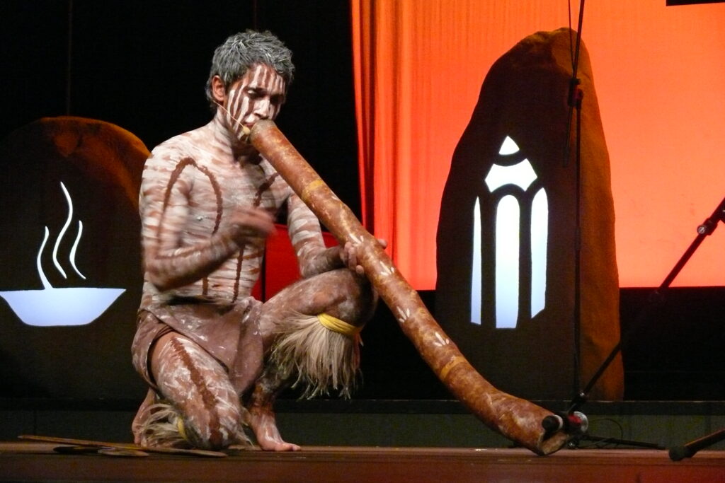 Djarrin painted up on stage playing didgeridoo
